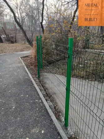 Забор из металлической сетки на проселочной дороге между деревьями