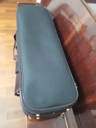 Чёрный футляр для музыкального инструмента на деревянной поверхности