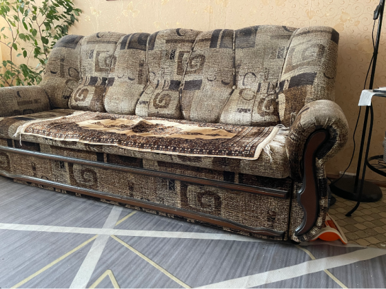 Жұмсақ диван жарқын жастықпен, жарықты қабырға декорының фонында