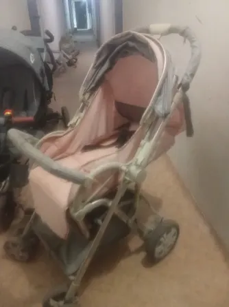 Детская коляска розового цвета в коридоре многоквартирного дома