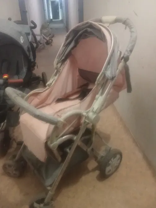 Детская коляска розового цвета в коридоре многоквартирного дома