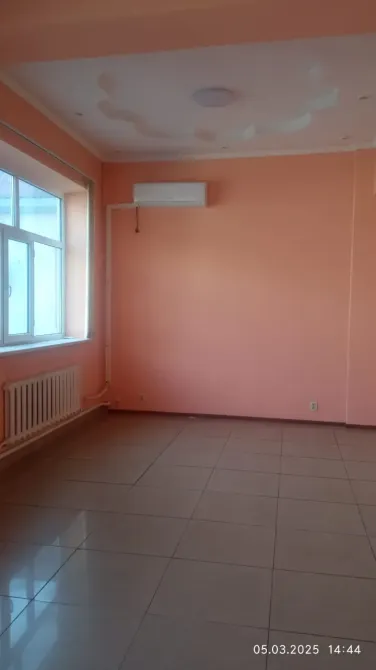 Пустое помещение с одним окном и аккуратной отделкой стен