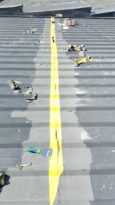 Строительная крыша с желтой лентой для герметизации шва