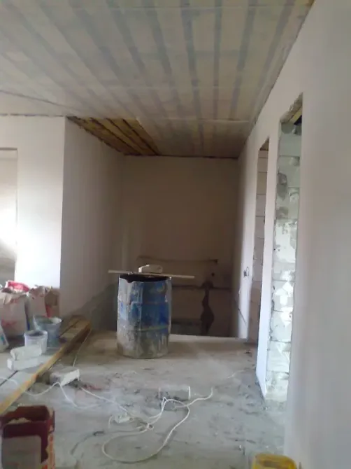 Неокрашенное помещение с потолком и строительными материалами