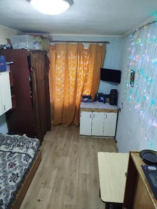 Небольшая комната с кроватью и столом, оранжевая штора