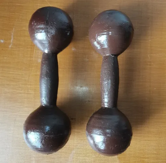 Два черных гантеля на деревянной поверхности