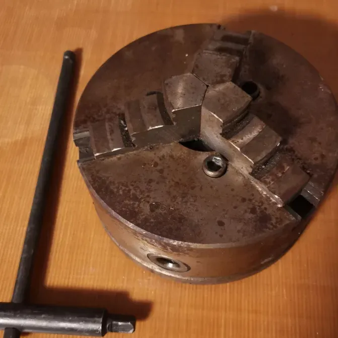 Чак для токарного станка на деревянной поверхности с ручкой