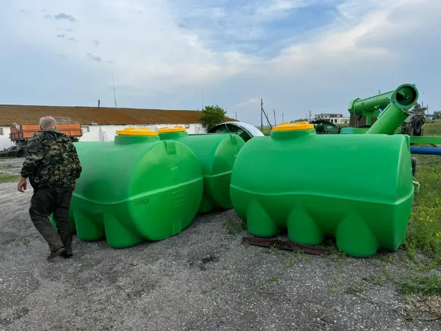 Мужчина в камуфляже рядом с зелеными резервуарами для хранения на открытом воздухе