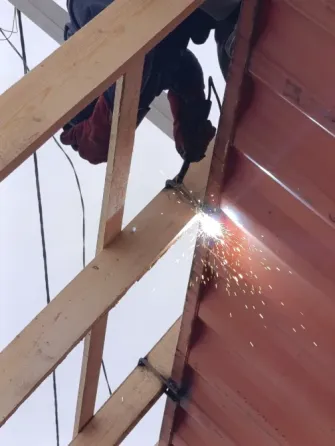 Рабочий, занимающийся сваркой на красном фоне