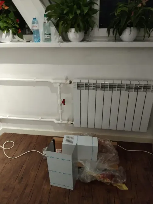 Радиатор отопления и трубы в комнате с растениями