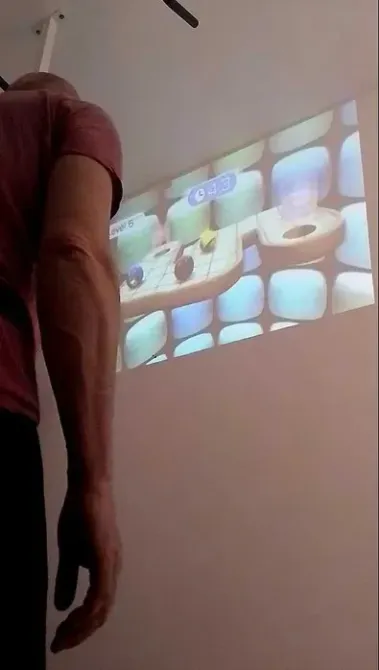 Мужчина взаимодействует с игрой на стене через проектор