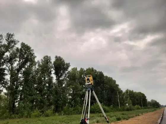 Техническое оборудование для геодезической съемки на фоне облачного неба и деревьев