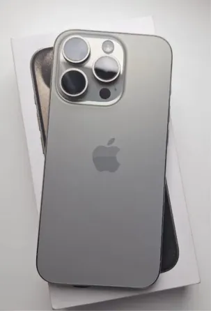 Смартфон Apple iPhone 13 Pro с серым задним корпусом и камерой с тремя объективами на фоне упаковки