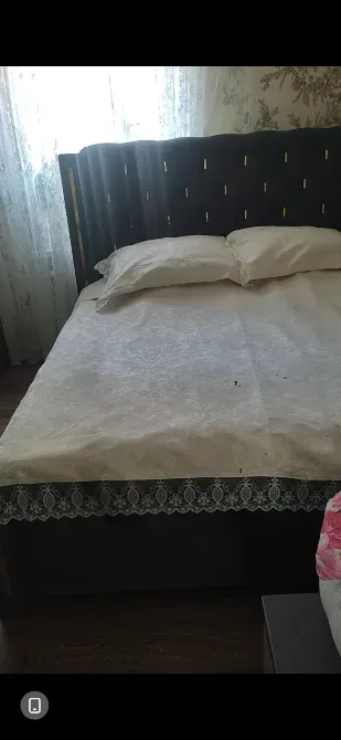 Төсек жастықтар мен жамылғының фонында мөлдір перде