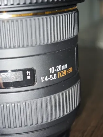 Объектив Sigma 10-20mm с чехлом на деревянном фоне
