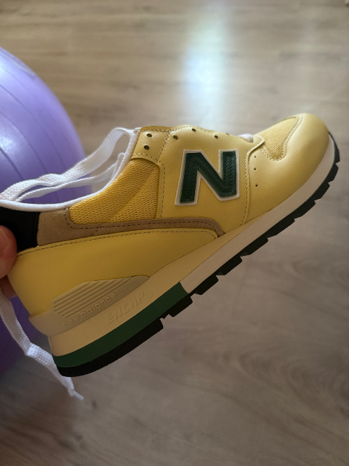 Один из кроссовок New Balance 996 желтого цвета на фоне интерьера