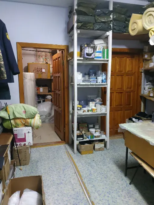 Сақтау бөлмесі, сөрелері мен басқа бөлмеге апарар есігі бар