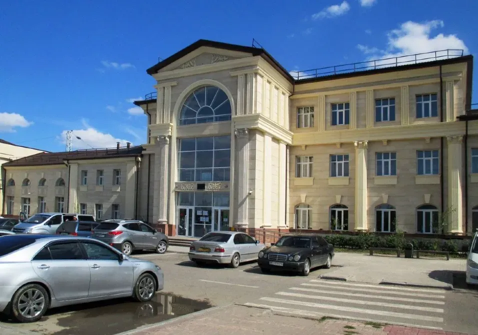 Фасад современного здания с машинами на парковке