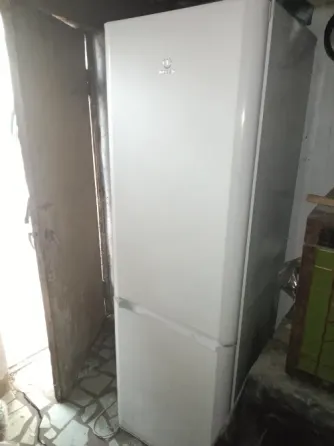 Холодильник стоит в комнате рядом с дверью
