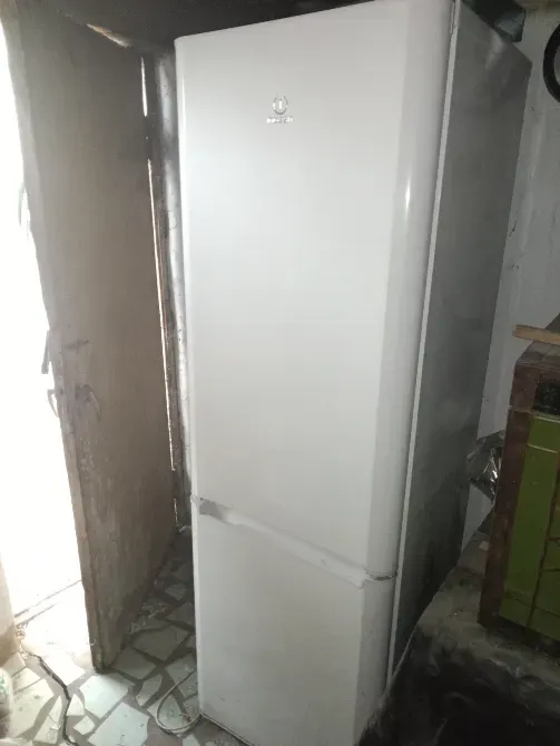 Холодильник стоит в комнате рядом с дверью