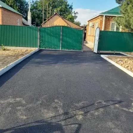Новое асфальтовое покрытие во дворе с зелеными забором