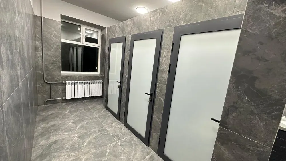Заманауи әжетханалар бөлу қабырғаларымен және сұр плиткамен