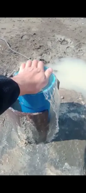Рука человека на синем ведре с водой на грязной поверхности