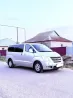 Жолдағы сұр минивэн Hyundai, үй мен қоршаудың жанында орналасқан.