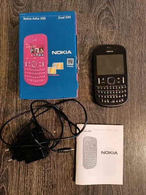 Телефон Nokia Asha 200 в упаковке с зарядным устройством и инструкцией
