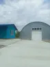 Көк үйлер мен бұлтты аспан фонындағы металл ангар