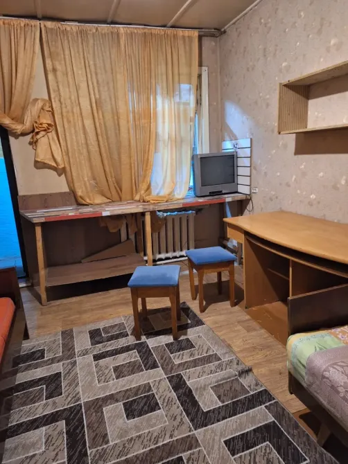 Комната с телевизором и столами, занавески на окнах