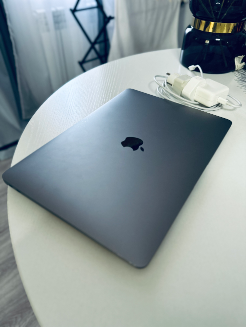 Лэптоп Apple на белом столе с зарядным устройством