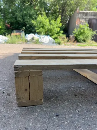 Деревянная паллета на улице, вокруг зелени и мусора