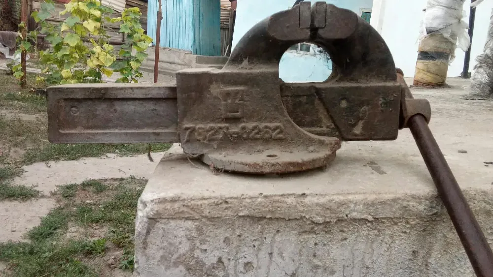 Старый металлический тиски на бетонной поверхности