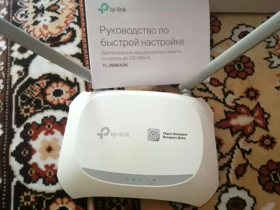 Маршрутизатор TP-Link TL-WR840N с инструкцией по быстрой настройке на фоне ковра