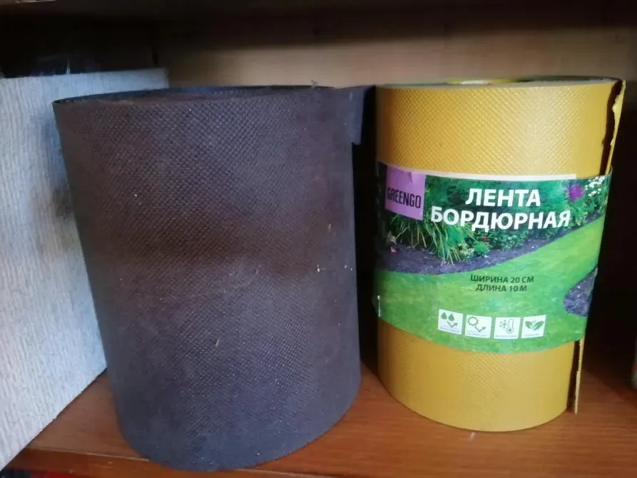 Картонная упаковка с бордюрной лентой и рулон черного материала, используемого в садоводстве